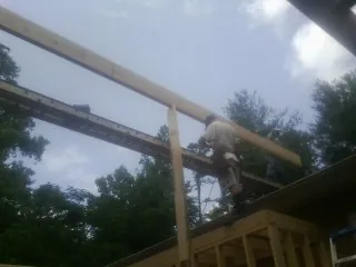 Carpenter setting a ridge beam over a new addition frame — Ice Dam Removal by Roofing Brothers in Kellogg